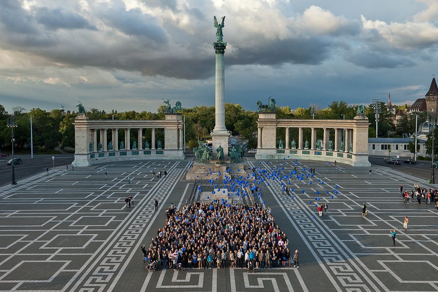 Große Gruppe steht auf einem weiten Platz, von oben fotografiert