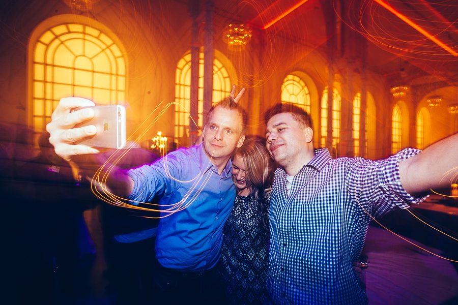 Drei Personen machen ein Selfie in einem festlich beleuchteten Saal