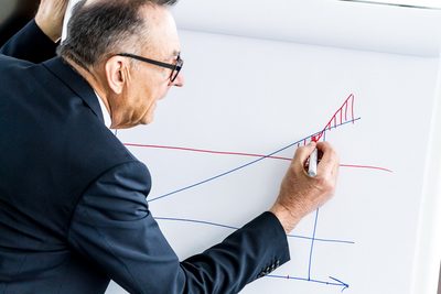 Mann im Anzug zeichnet ein Diagramm auf ein Flipchart